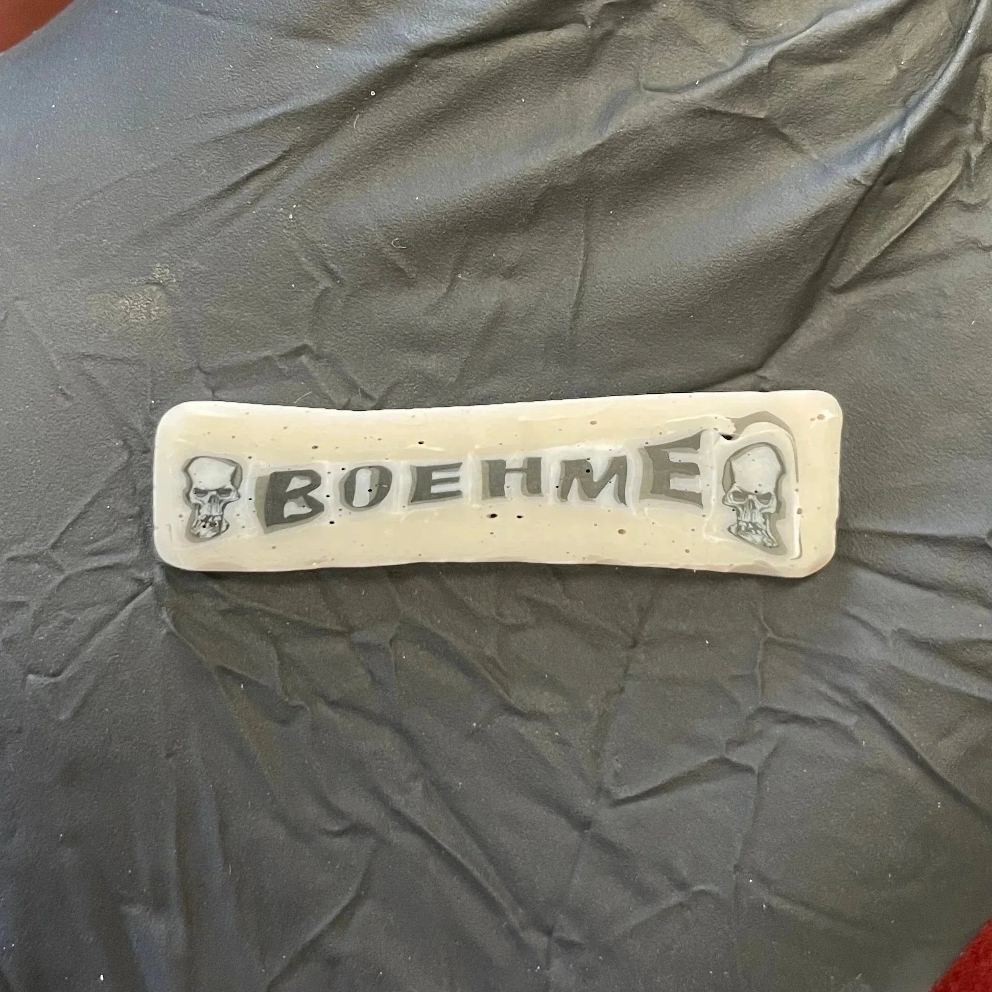 Handmade glass label with 'BOEHME' text and skull designs on textured background