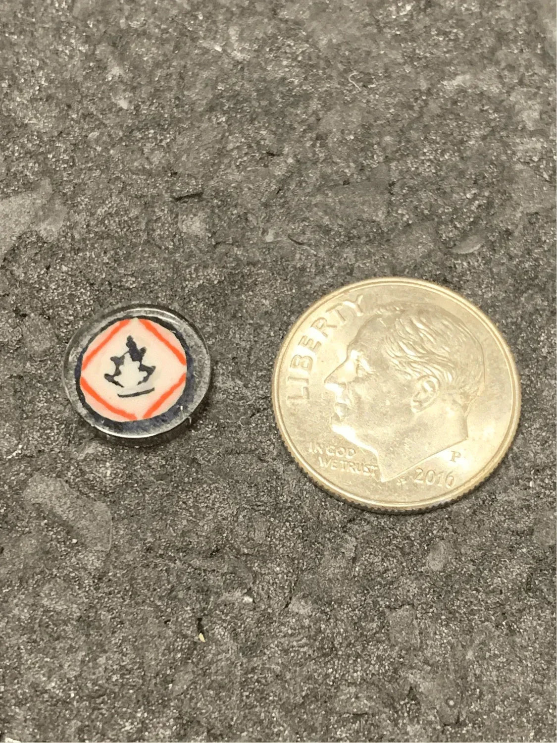 Small glass ash catcher with flame design next to dime for scale, heady glass accessory