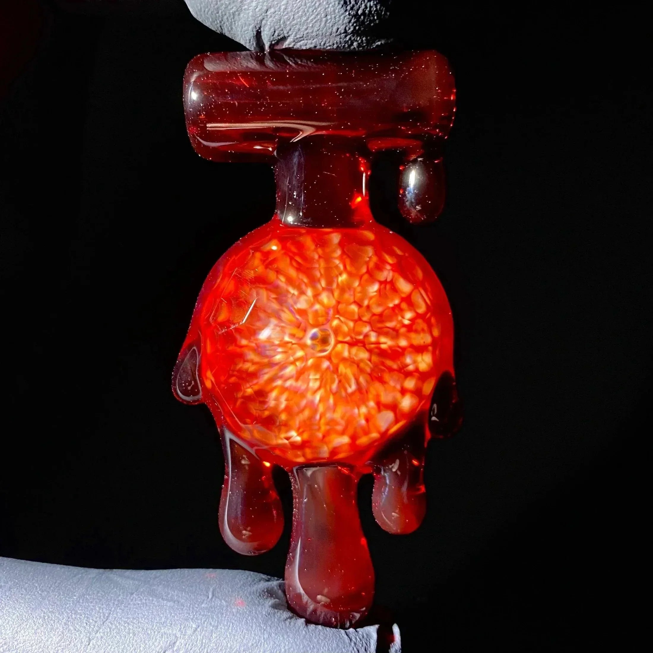 Handblown red glass carb cap with molten drip design on black background
