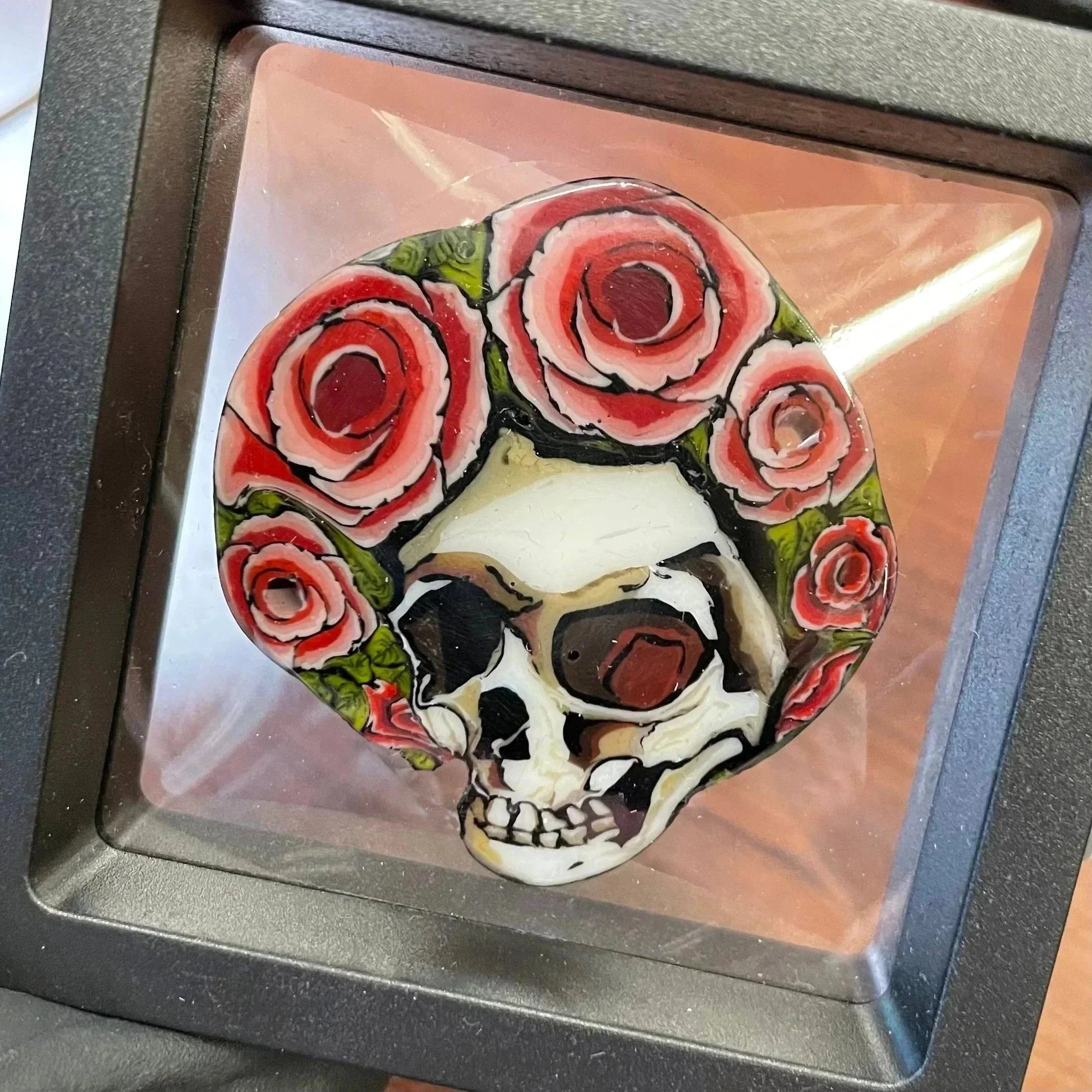 Heady glass art featuring a skull with red rose crown, displayed in a protective frame