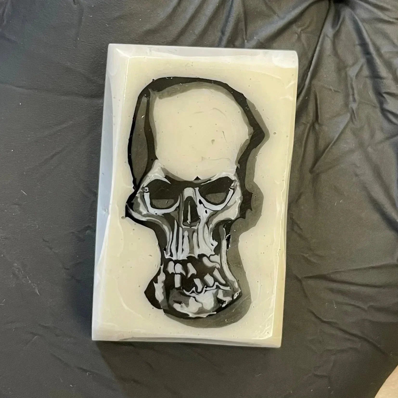 Rectangular white resin block with an embedded black and white skull design, on gray surface