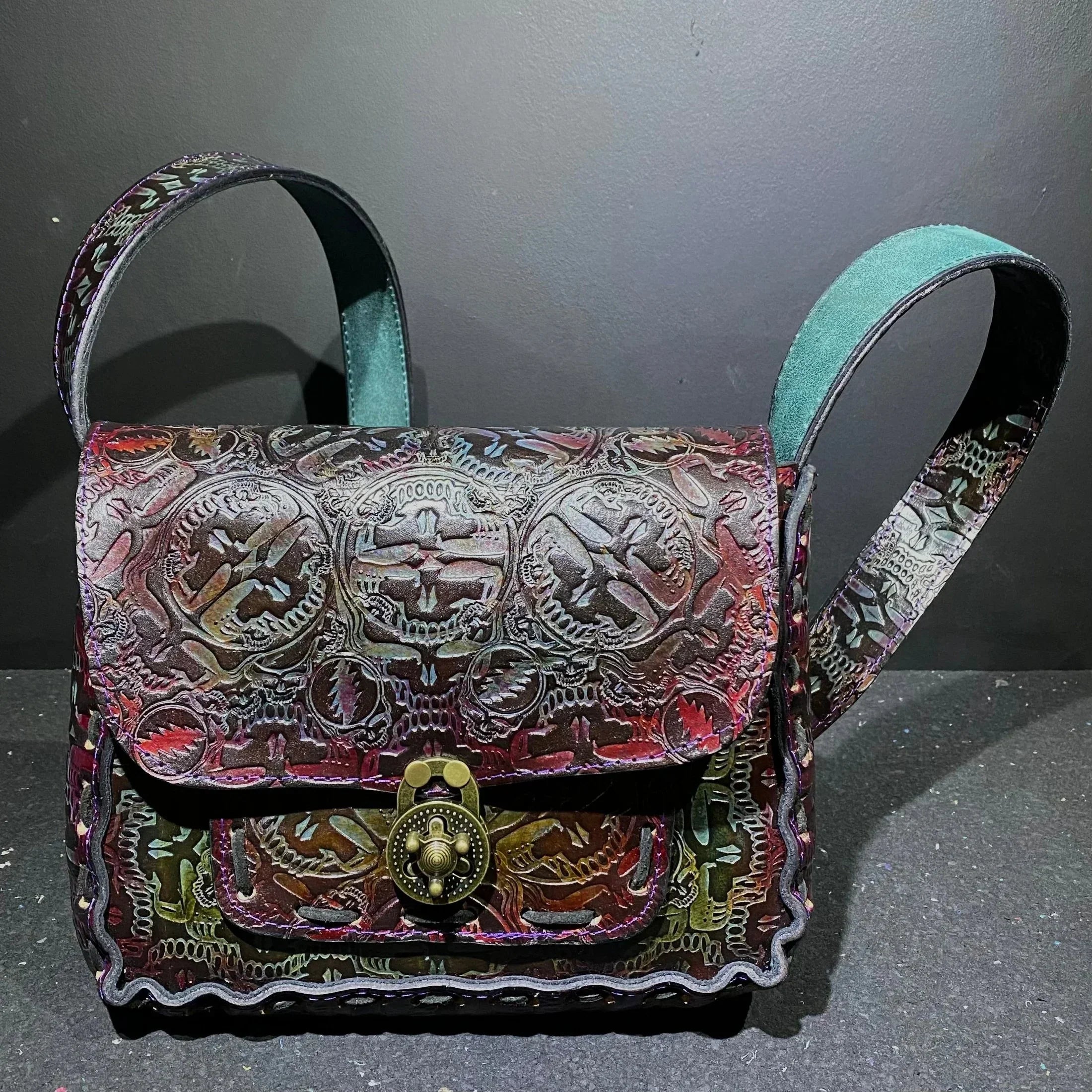 Handmade embossed leather shoulder bag with brass clasp and intricate skull patterns