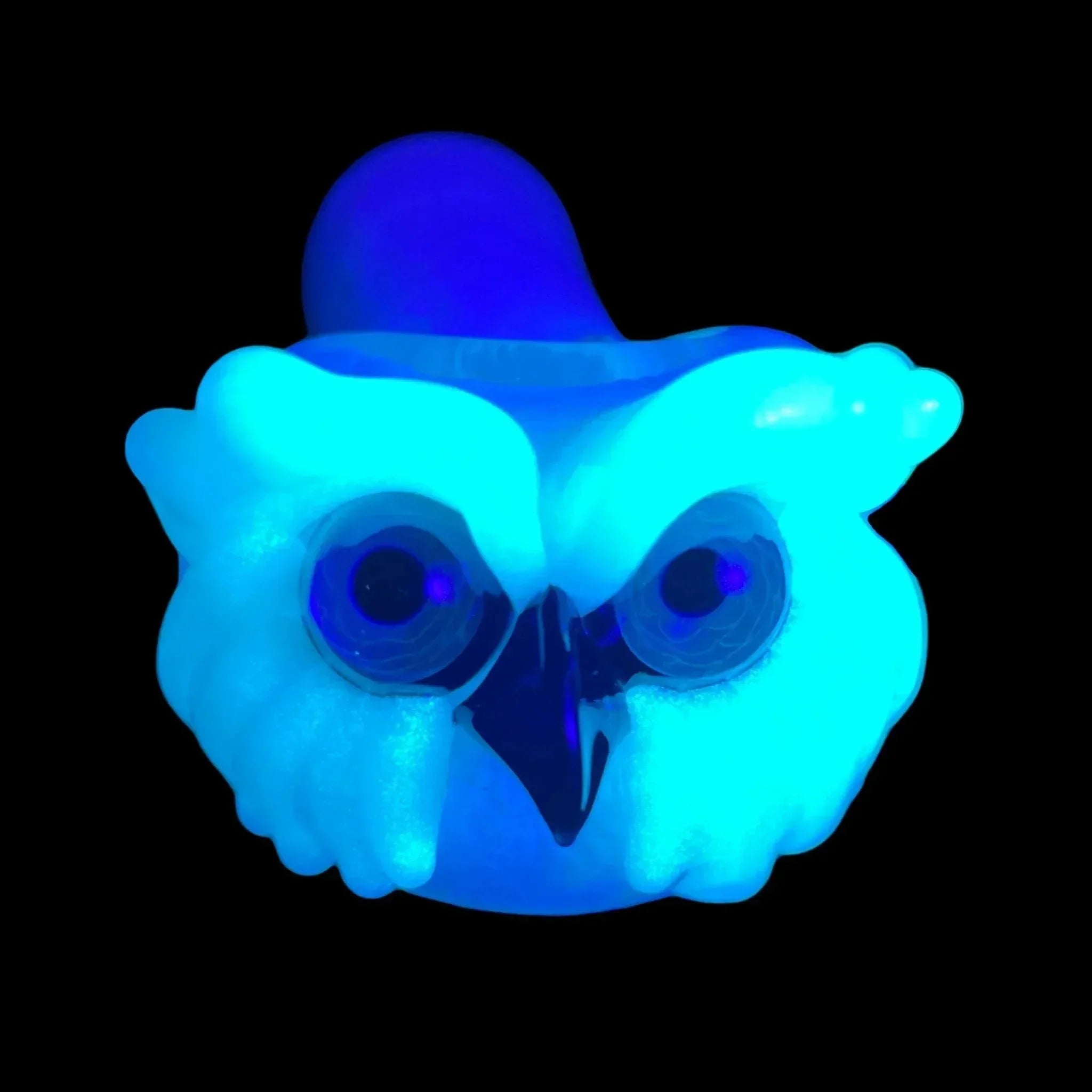 Glow-in-the-dark owl glass pipe with blue UV reactive color on black background