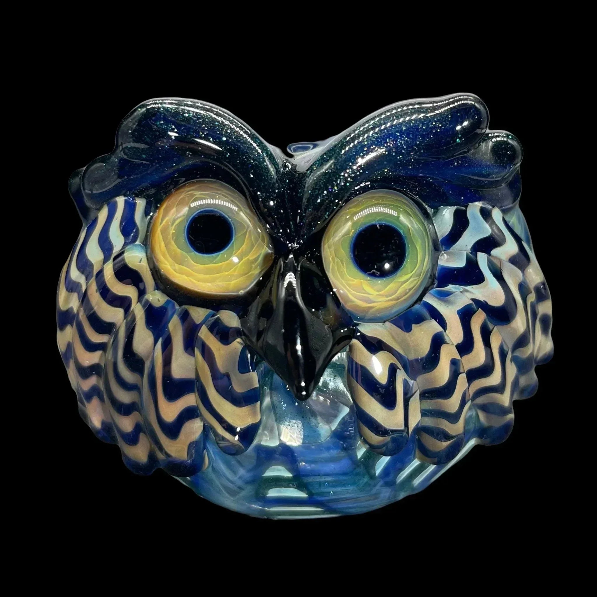 Handcrafted glass owl pipe with blue and yellow swirled patterns on a black background