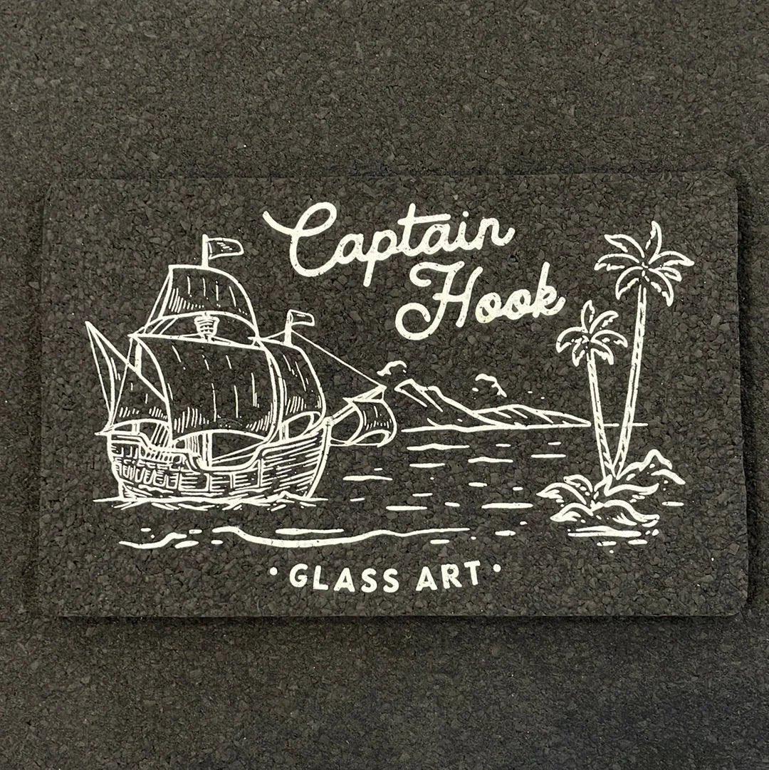 Captain Hook Glass Art mat with white ship, island, and palm tree illustration on black background
