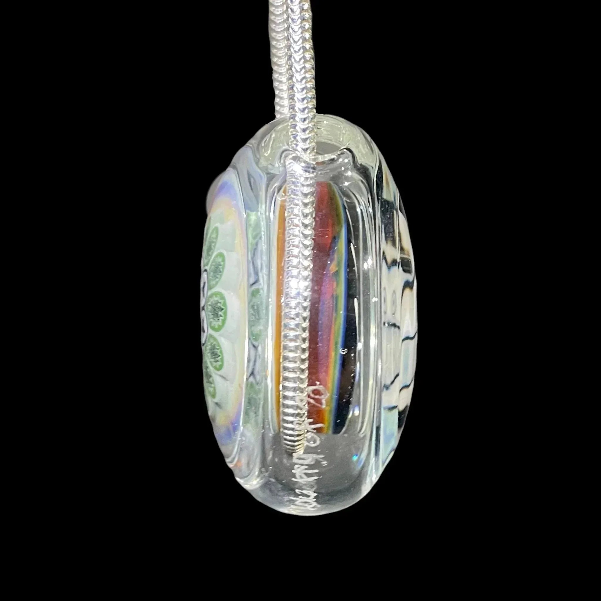 Handmade glass pendant with green millefiori design on silver chain, black background