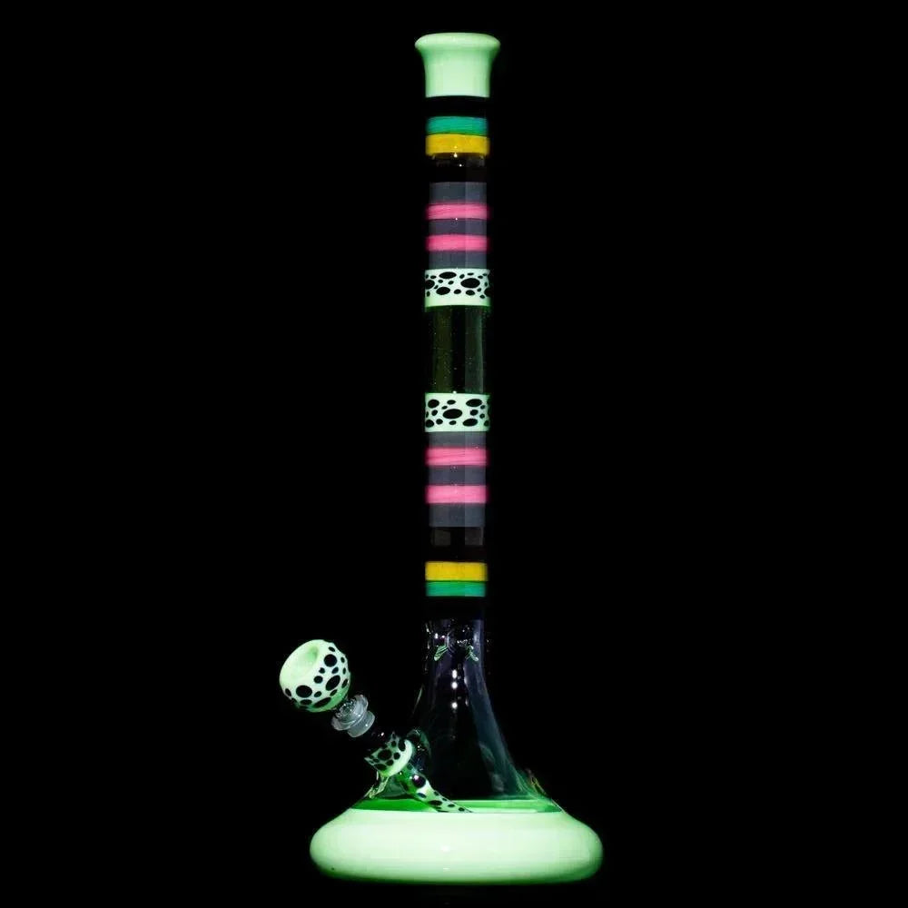 Colorful striped glass water pipe with glowing accents and polka dot bowl on black background