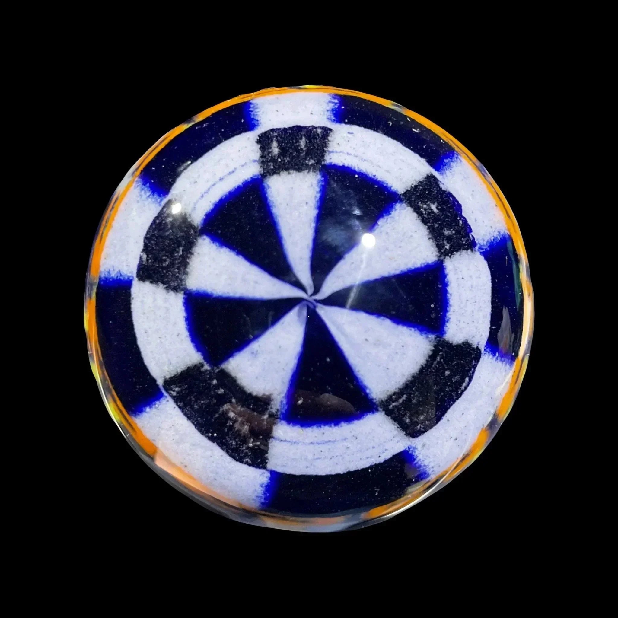 Handcrafted glass marble with blue and white spiral pattern and orange rim on black background