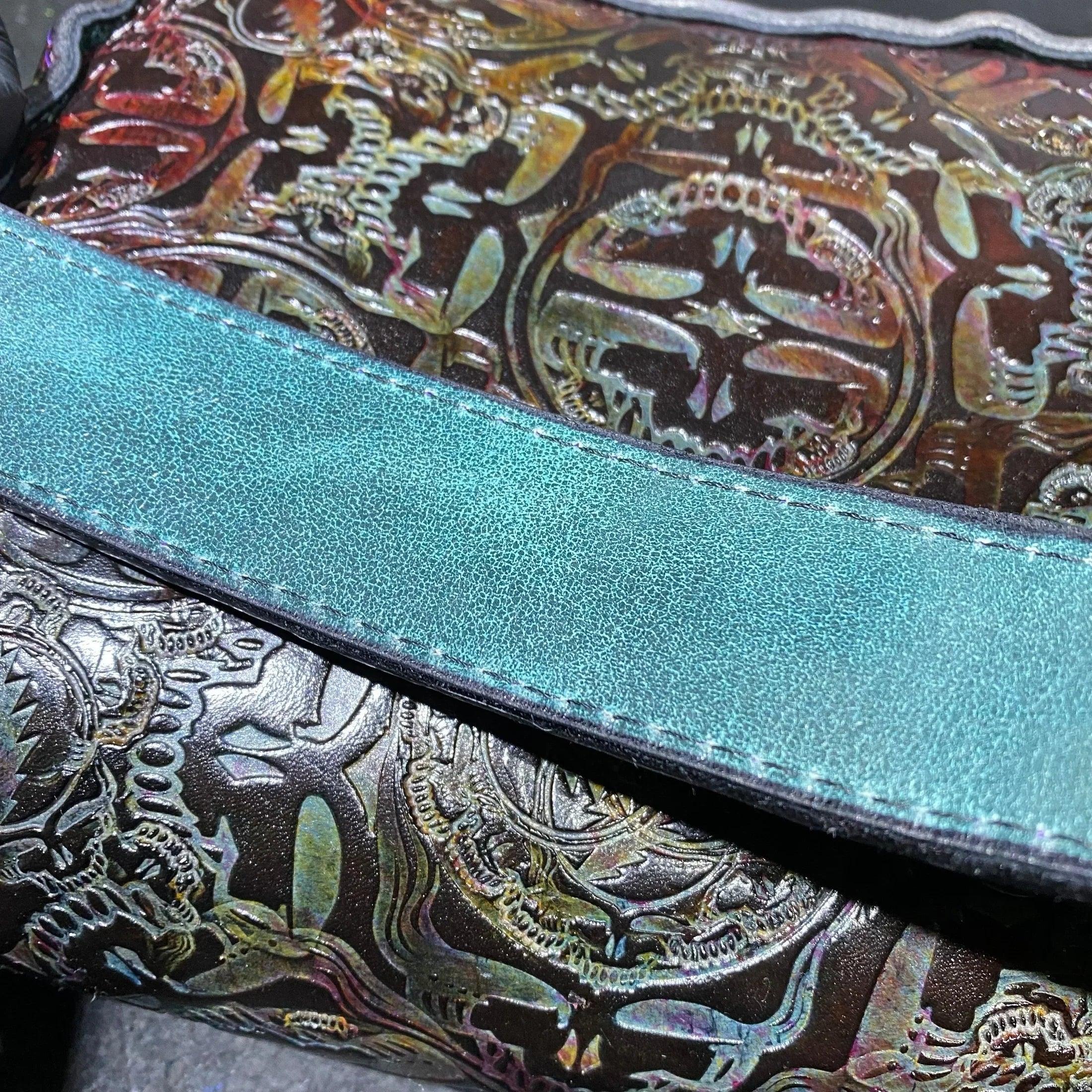 Close-up of iridescent embossed leather pouch with teal strap, detailed texture visible
