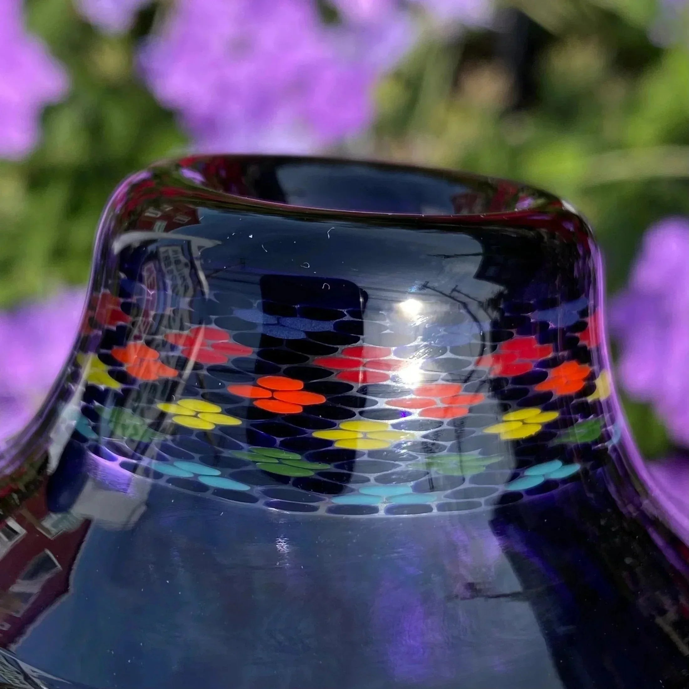 Close-up of colorful patterned glass pipe with rainbow accents and floral background