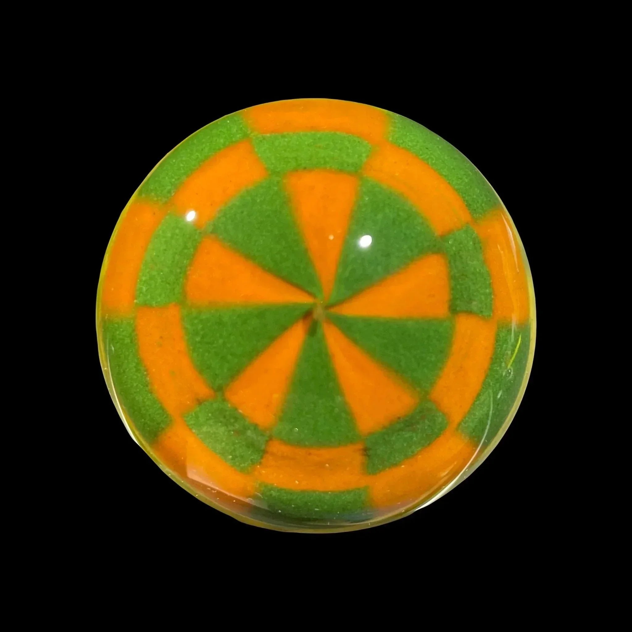 Colorful glass marble with orange and green geometric pattern on black background