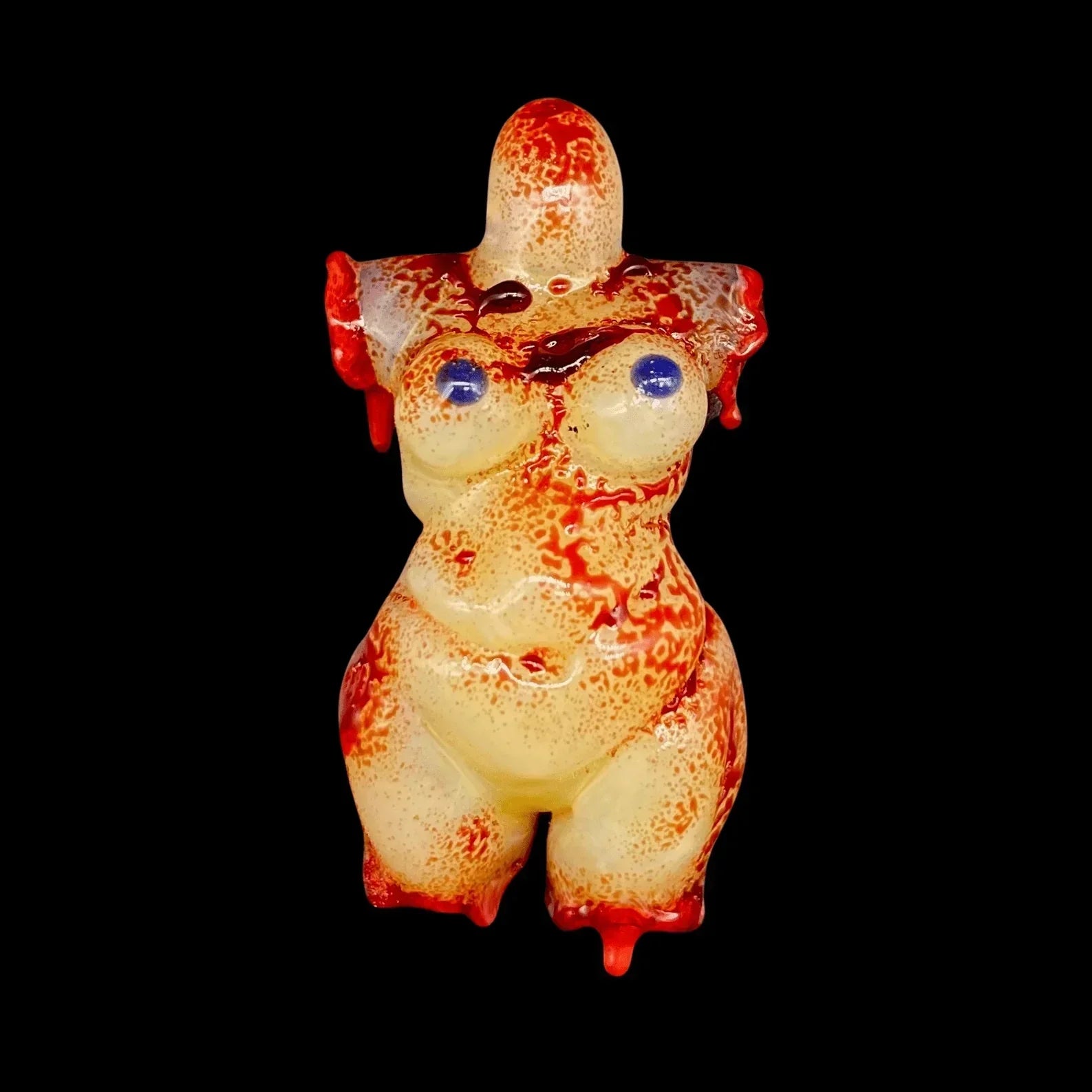 Hand-blown glass figurine of a curvy human torso with red and blue accent details on black background