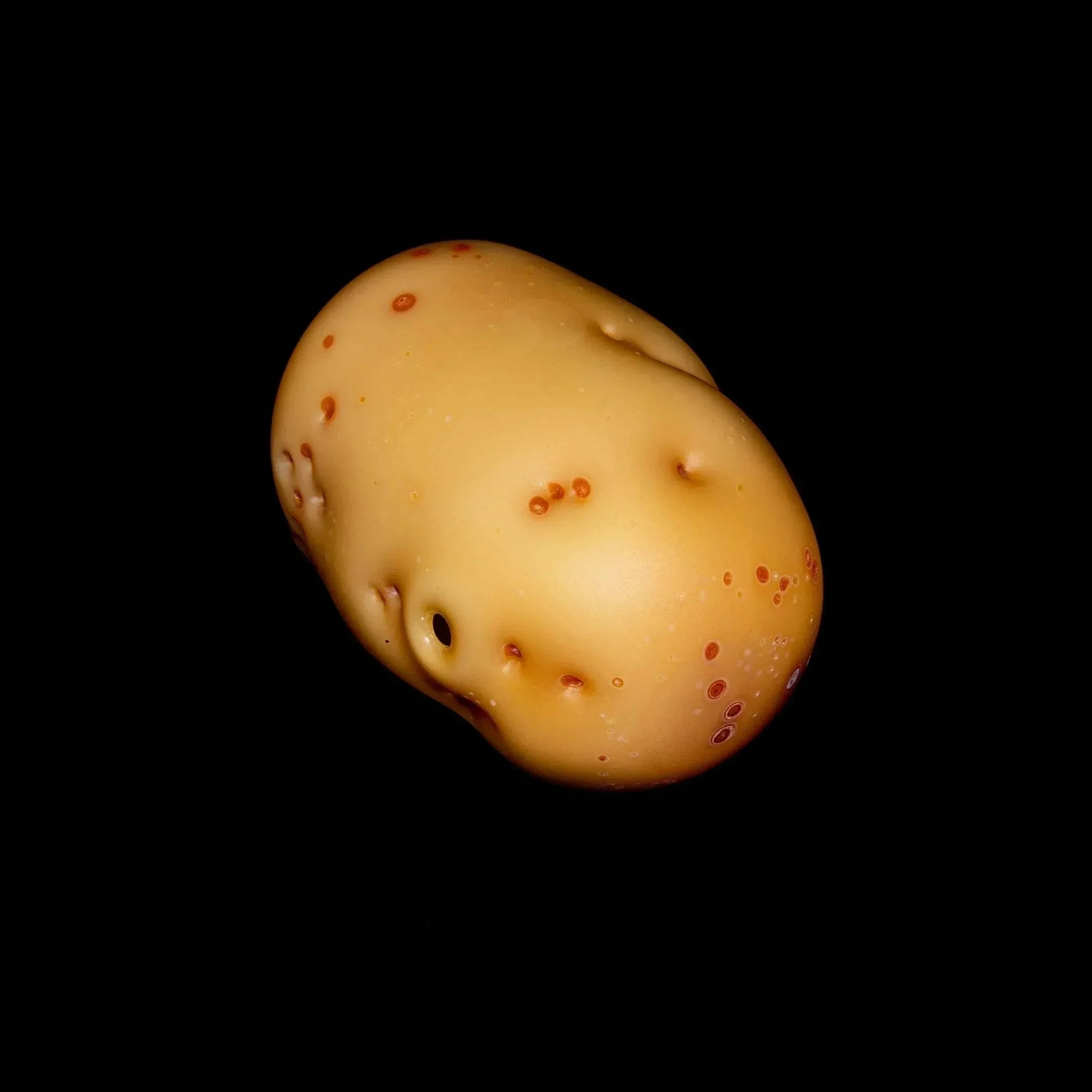 Realistic glass hand pipe shaped like a potato with brown speckles on a black background