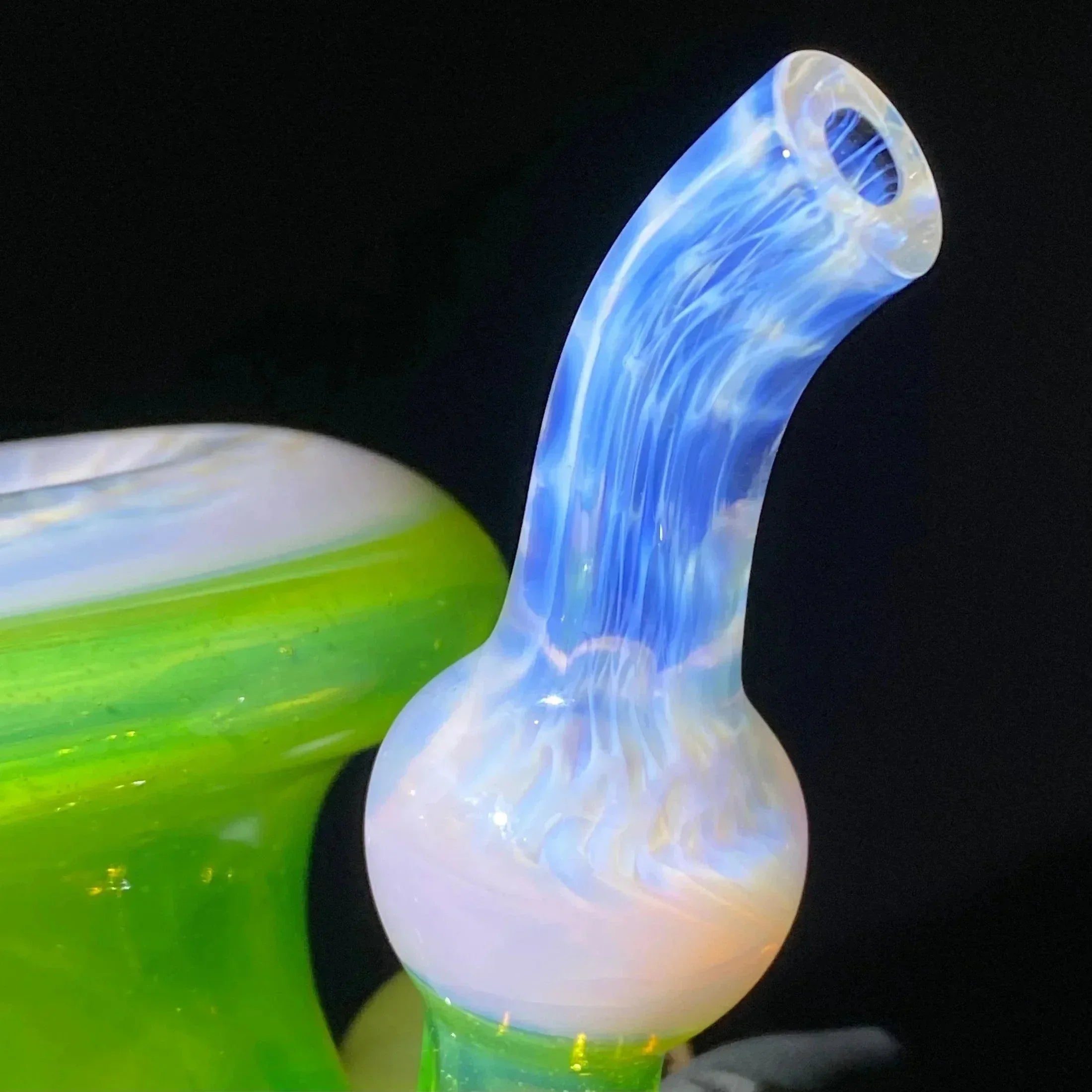 Close-up of a colorful glass water pipe with vibrant green and blue swirled mouthpiece