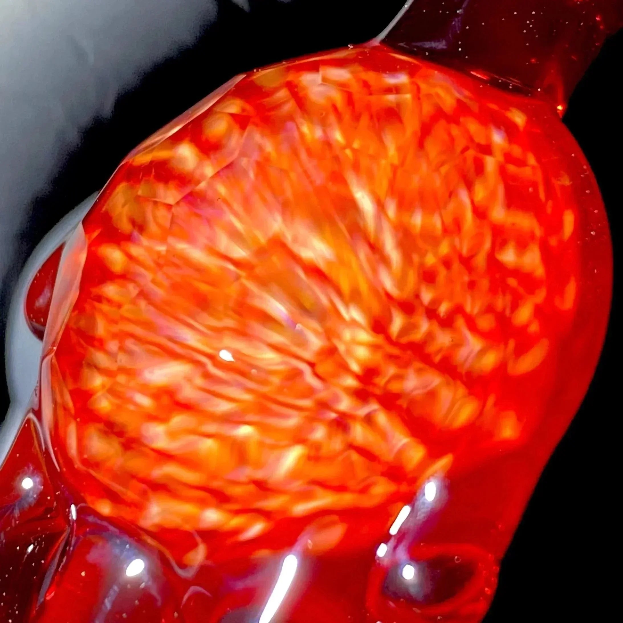 Close-up of a handblown red and orange glass pipe with vibrant swirling patterns