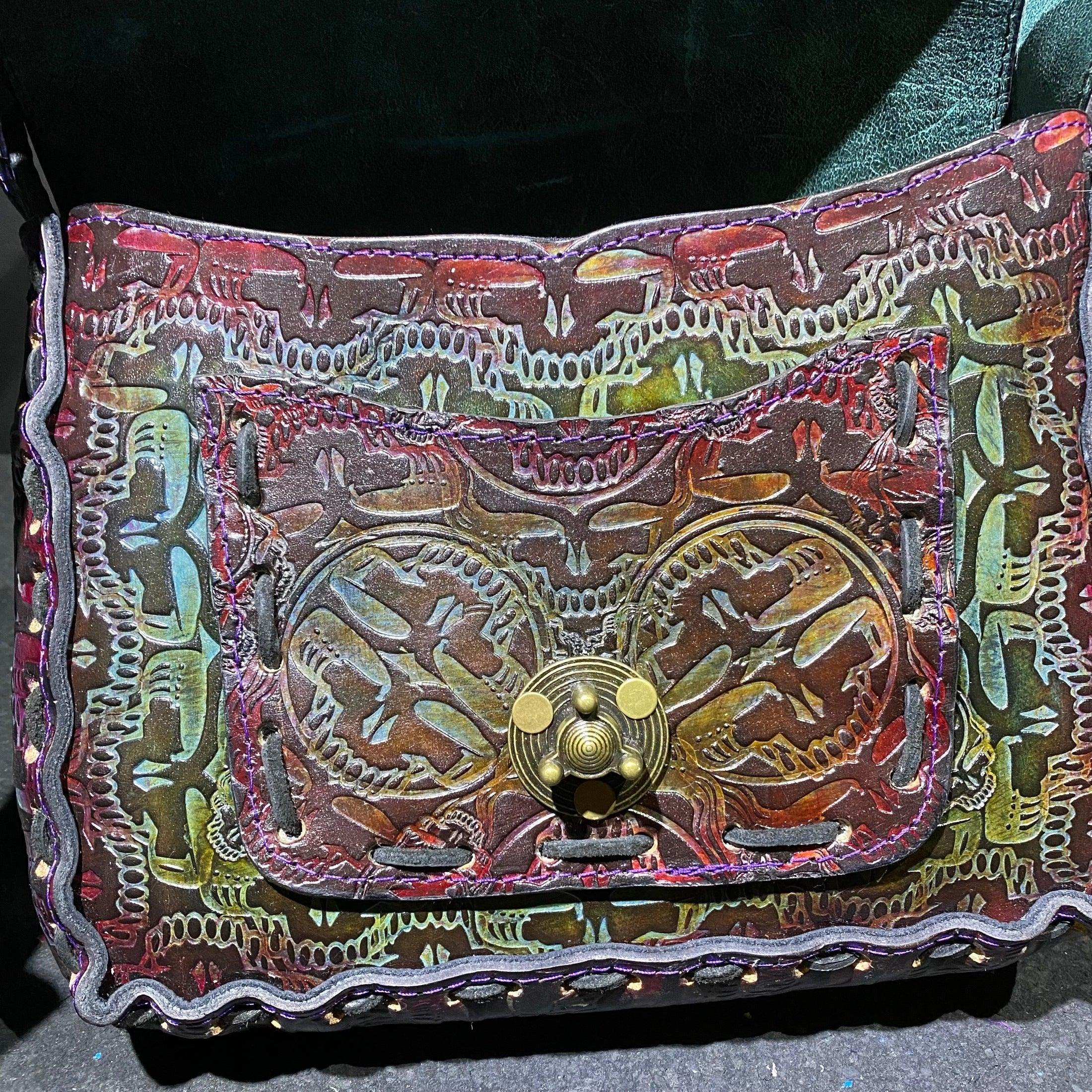 Handcrafted leather pouch with embossed skull pattern and brass clasp, colorful finish