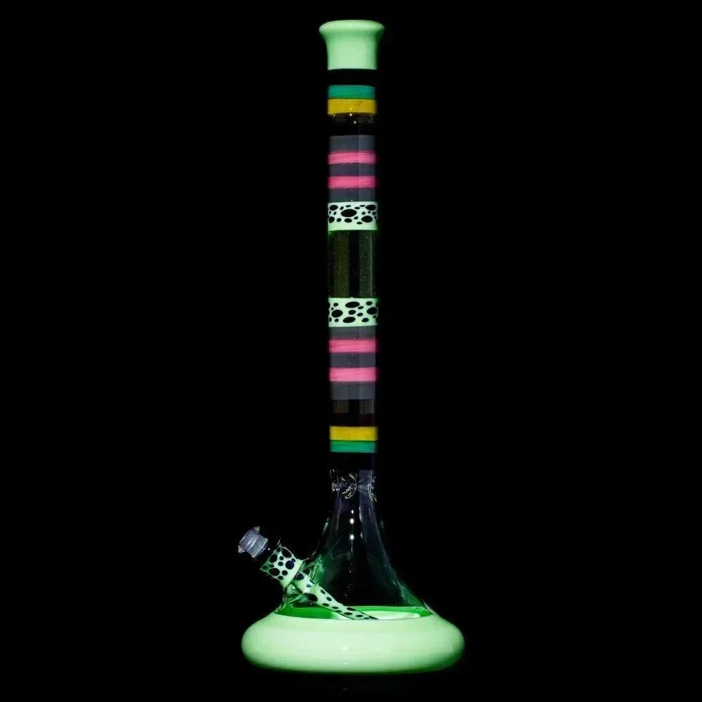 Colorful glass water pipe with neon green base, striped neck, and spotted accent, isolated on black background.