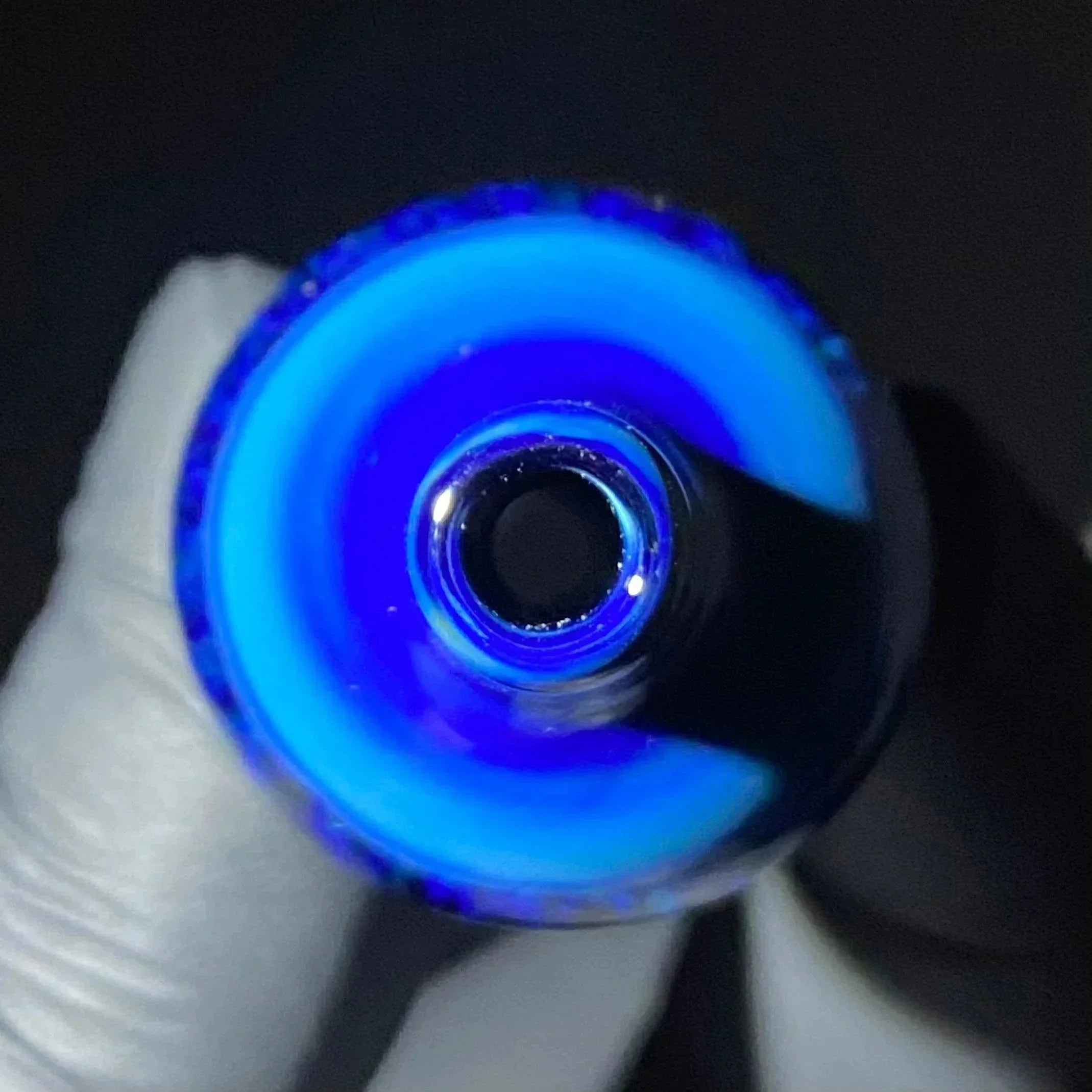 Close-up of blue hand-blown glass pipe mouthpiece with vibrant swirling pattern