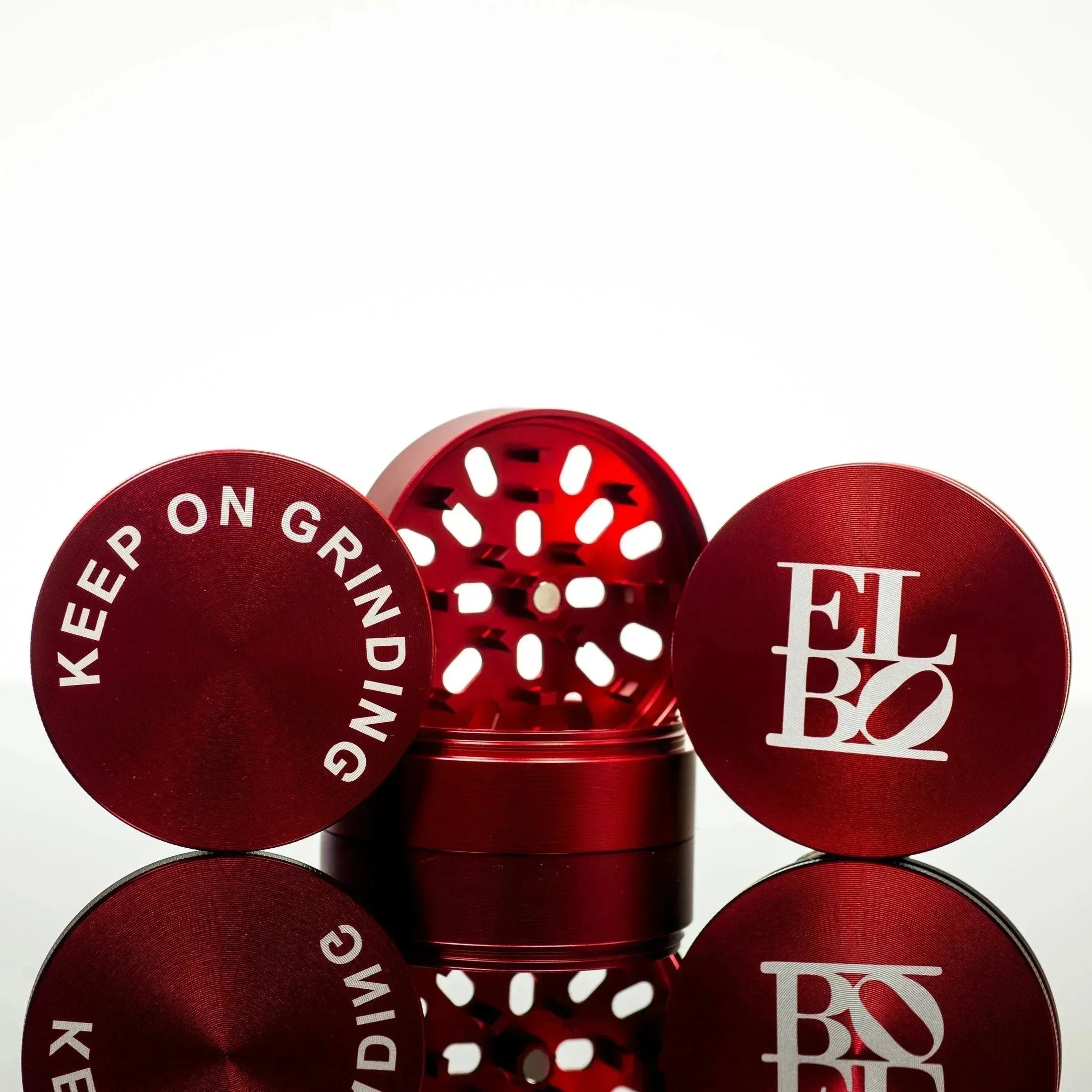 Red ELBO grinder with 'Keep On Grinding' lid, featuring premium metal construction and sleek design
