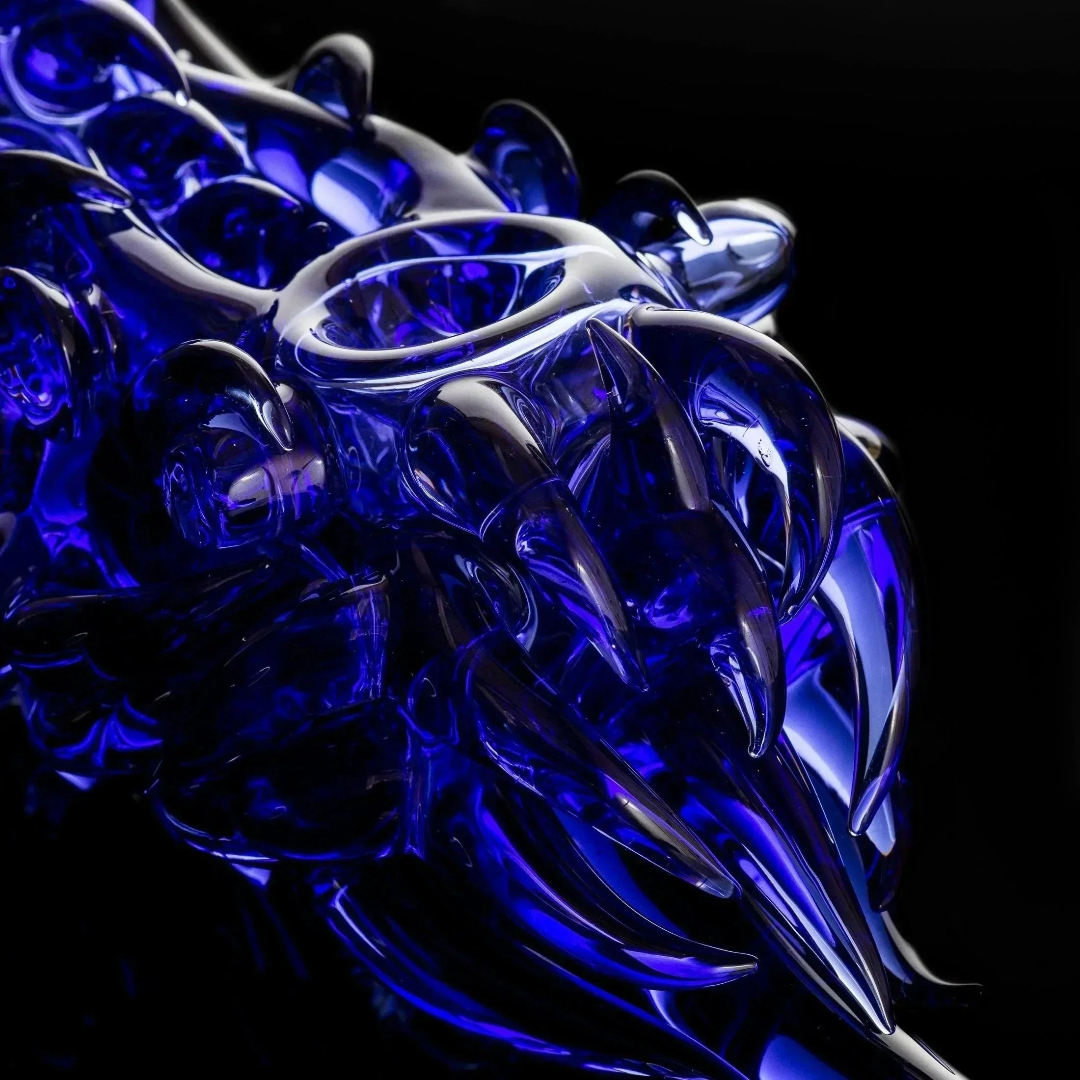 Deep blue heady glass pipe with intricate swirls and sharp accents, showcasing premium craftsmanship.