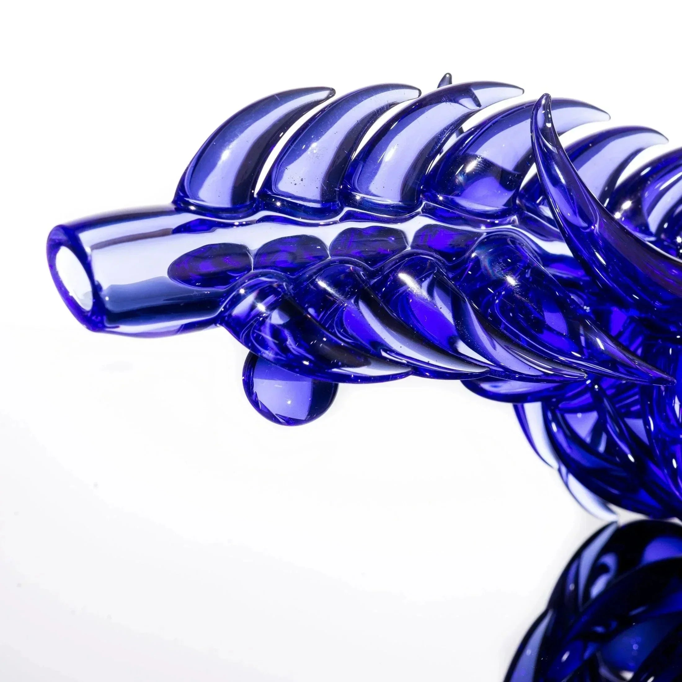 Vibrant blue glass pipe with intricate dragon-scale design, showcasing heady glass artistry.