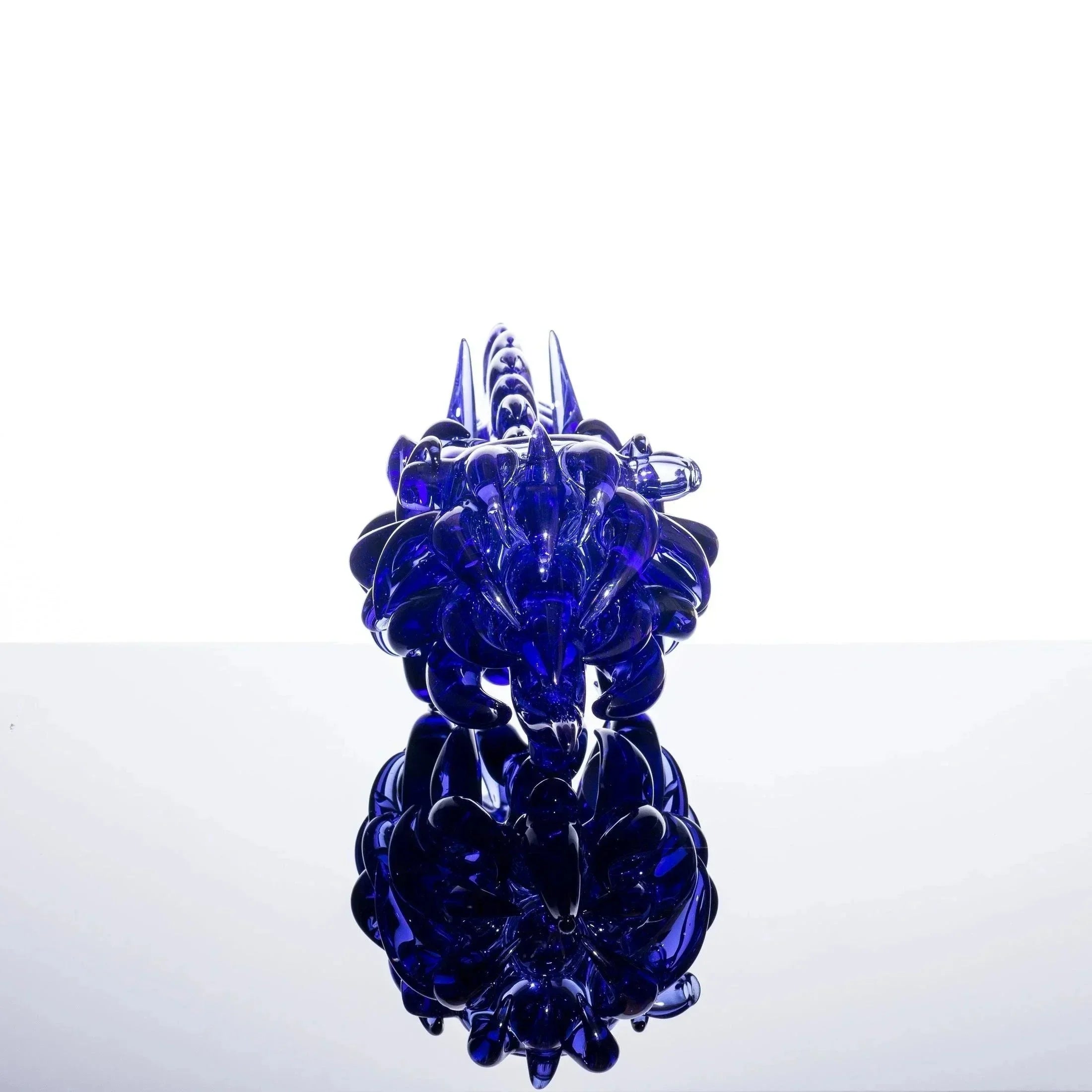Deep blue heady glass sculpture with intricate spikes and bubbles, reflective surface
