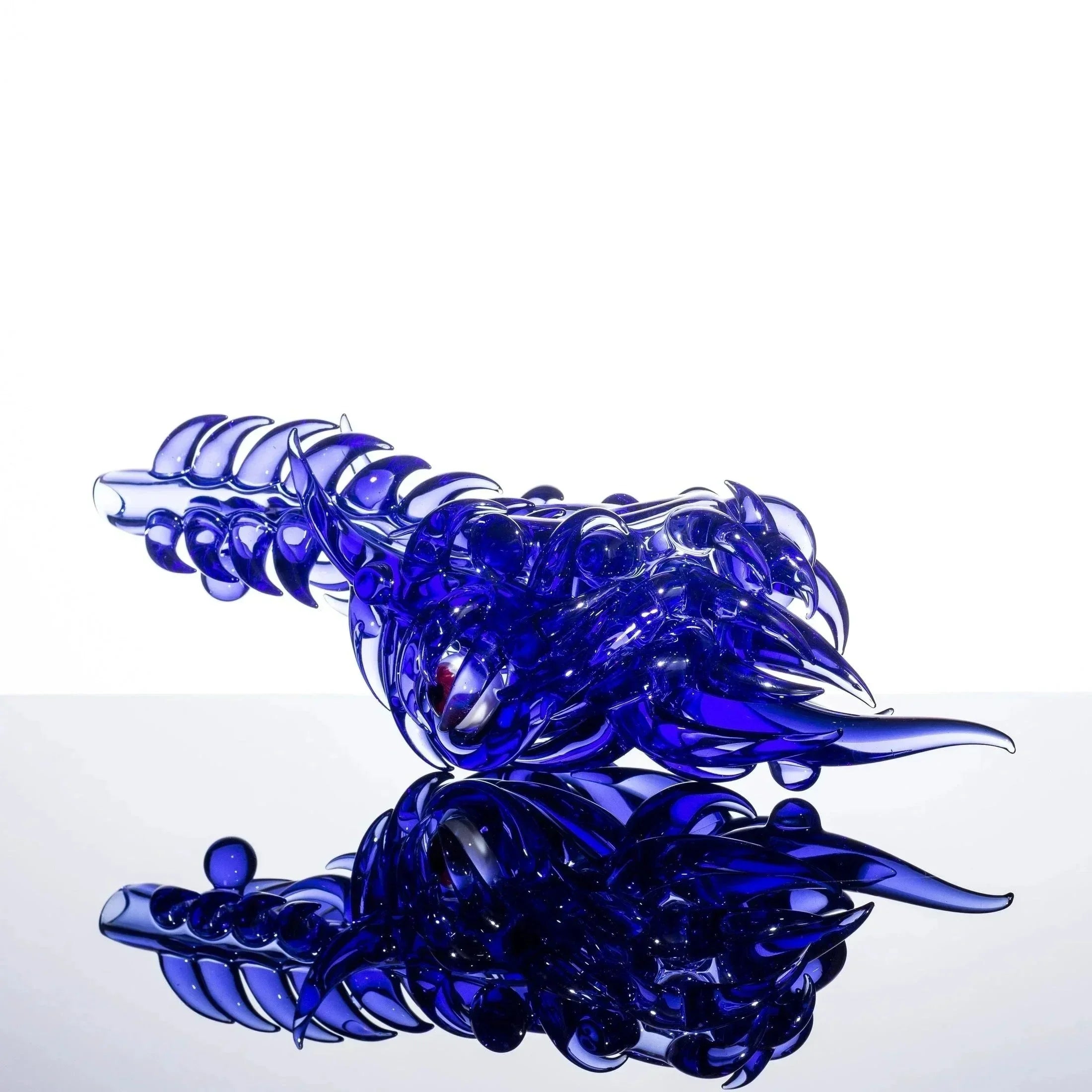 Deep blue heady glass pipe with intricate dragon design, reflective surface, premium smoke accessory