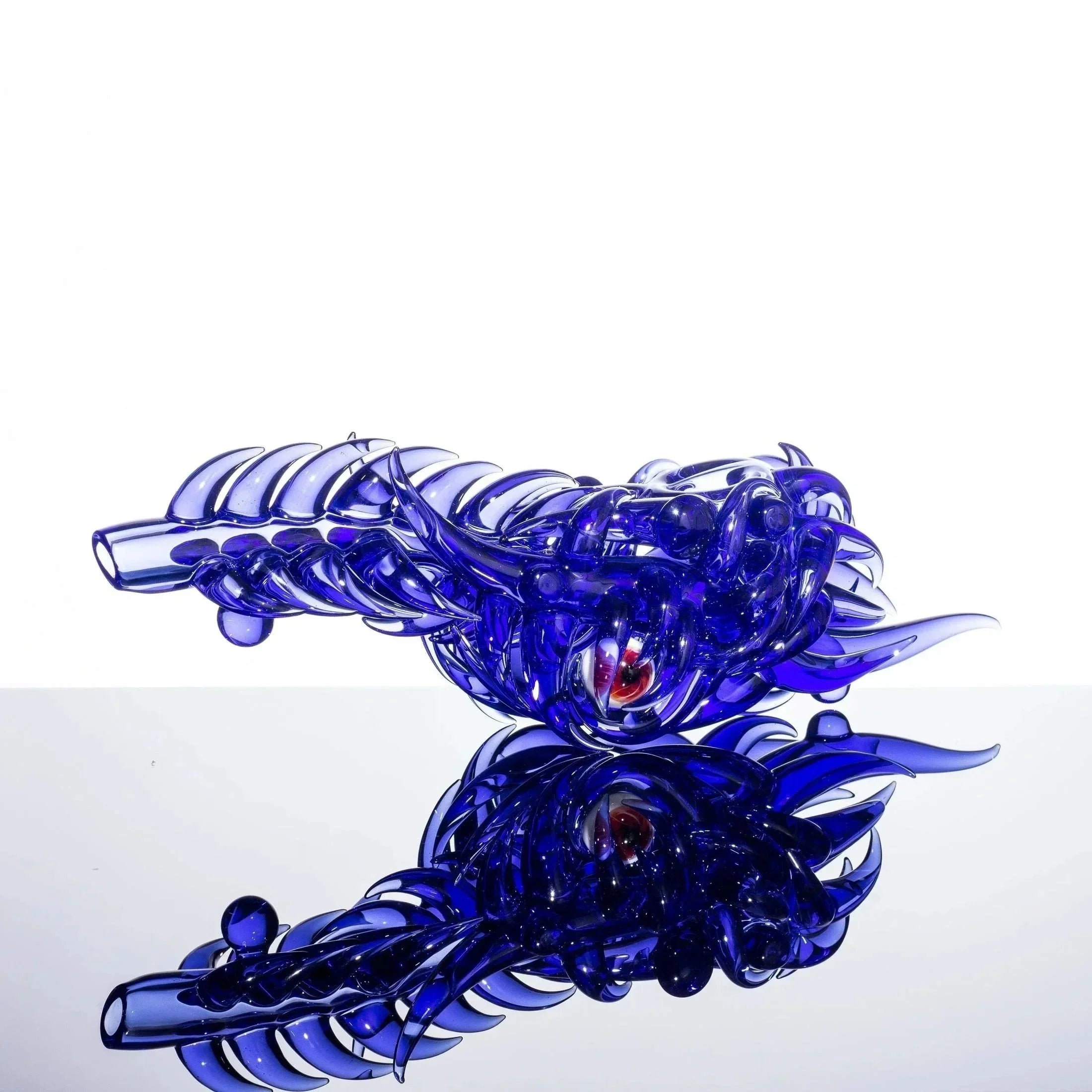 Blue dragon-shaped glass pipe with red eye, reflective surface, heady glass art