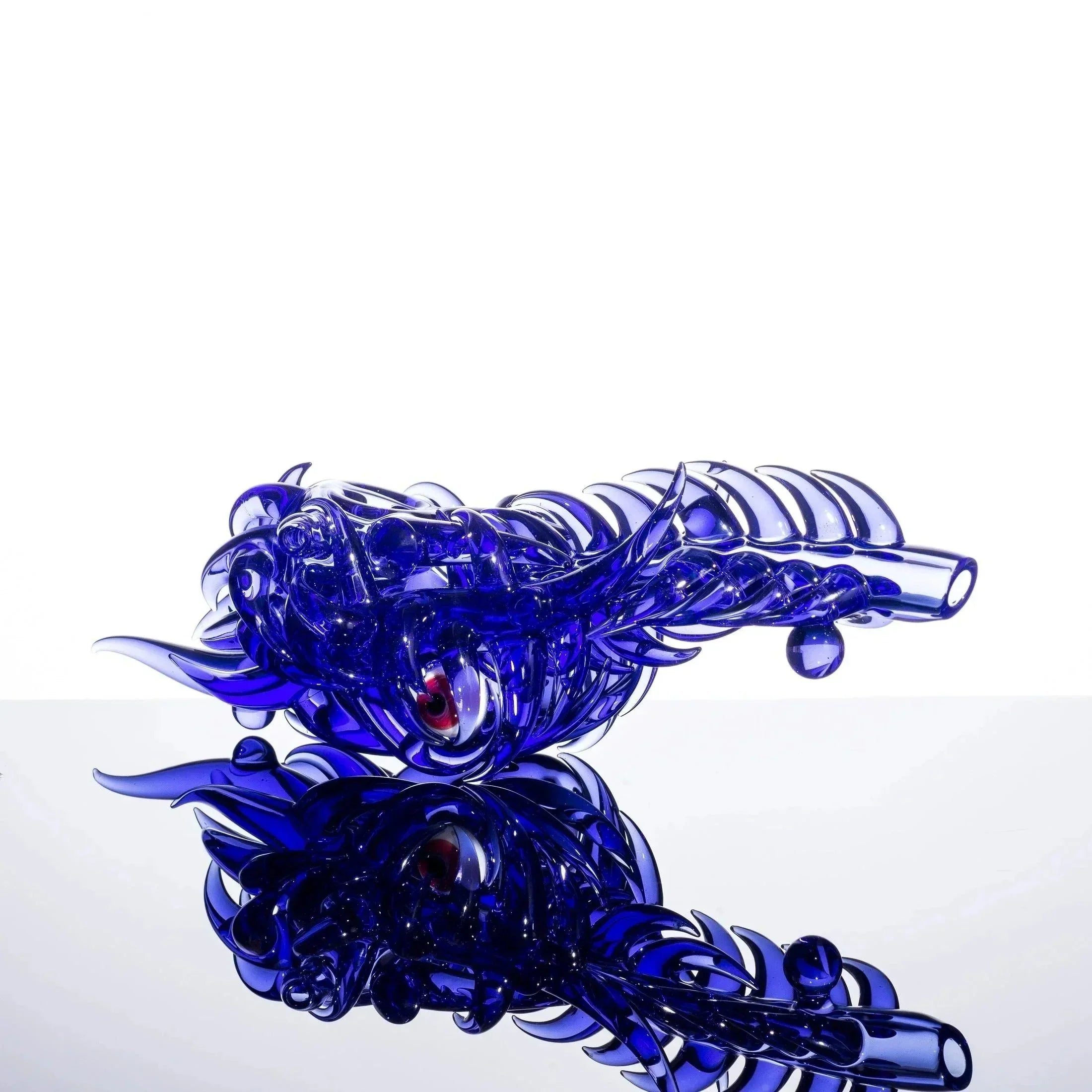 Blue glass dragon pipe with red eyes, intricate scales, and reflective surface, heady glass art piece