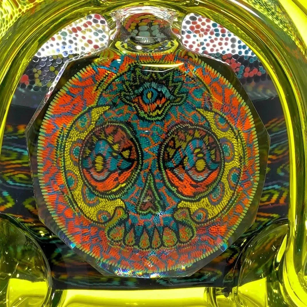 Intricate skull glass art with vibrant patterns in yellow, orange, blue, and green hues