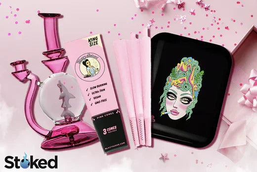 Pink glass water pipe with unicorn, pink cones, and black rolling tray with colorful face illustration.