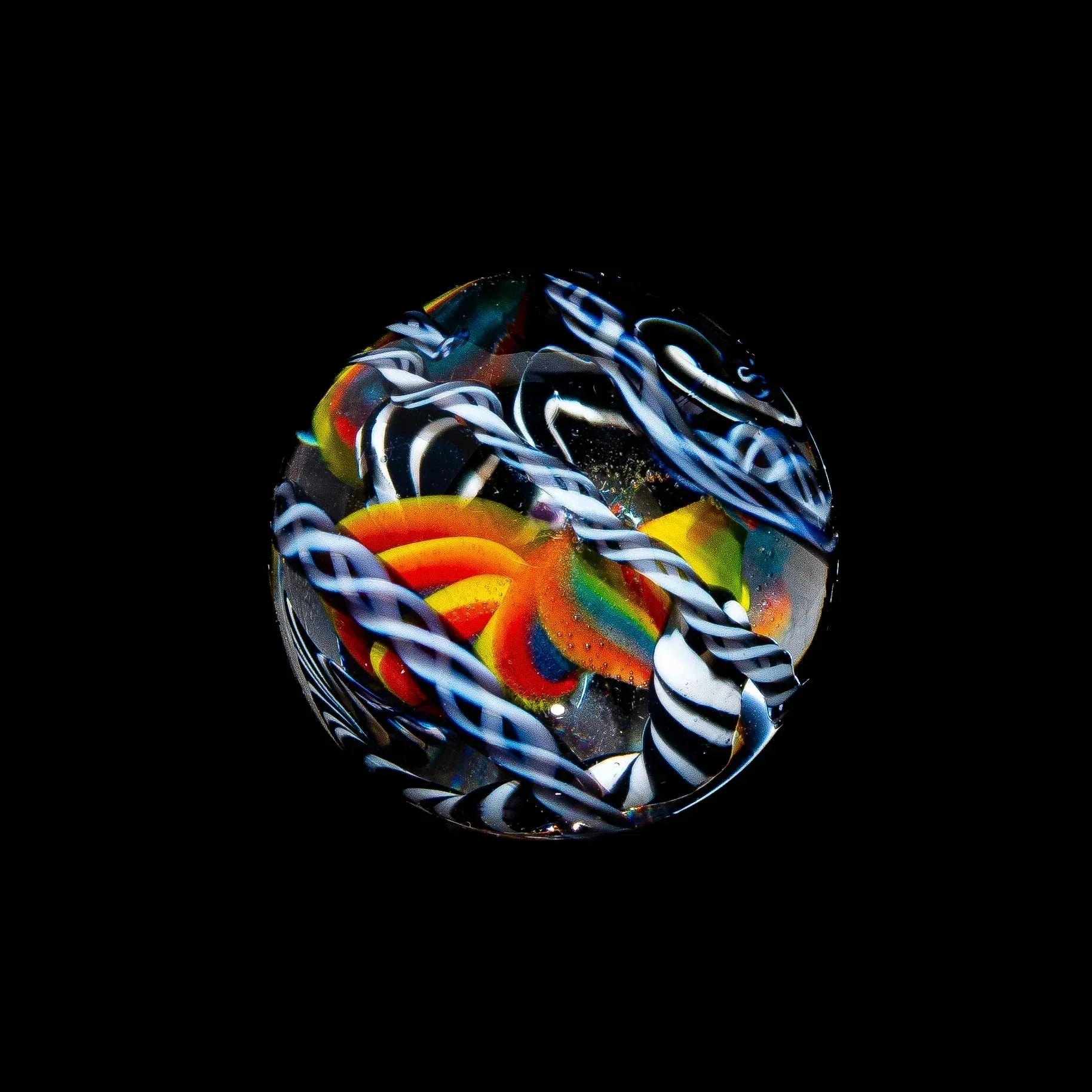 Handcrafted glass marble with rainbow flower design and blue-white twisted accents on black background
