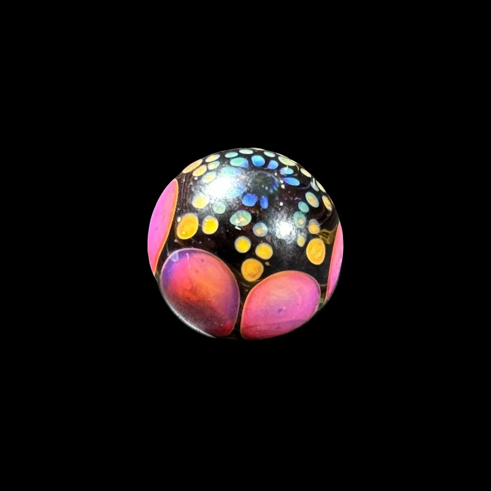 Colorful glass marble with yellow, blue, and pink accents on a black background