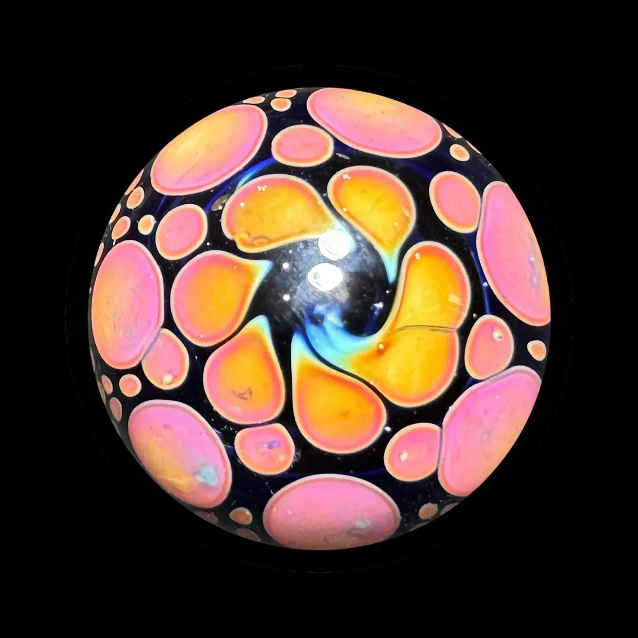 Colorful heady glass marble with swirling orange and pink pattern on black background