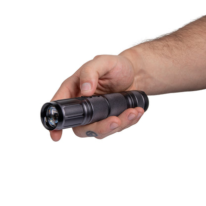 Hand holding a black textured flashlight on white background