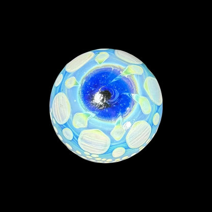 Hand-blown glass marble with blue and white cosmic swirl pattern on black background