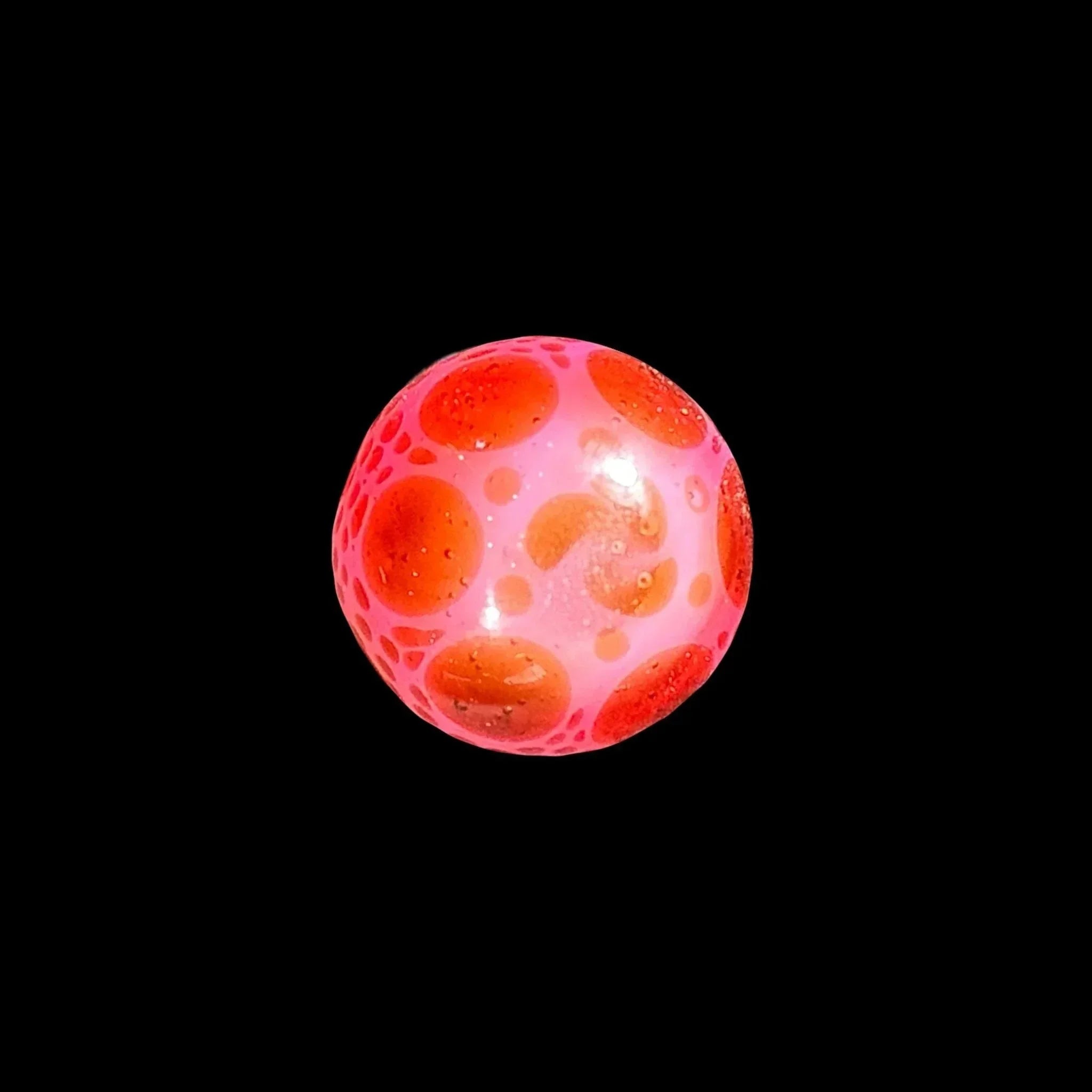 Pink and orange glass marble with bubble details on black background