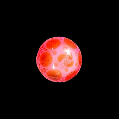 Pink and orange glass marble with bubble details on black background