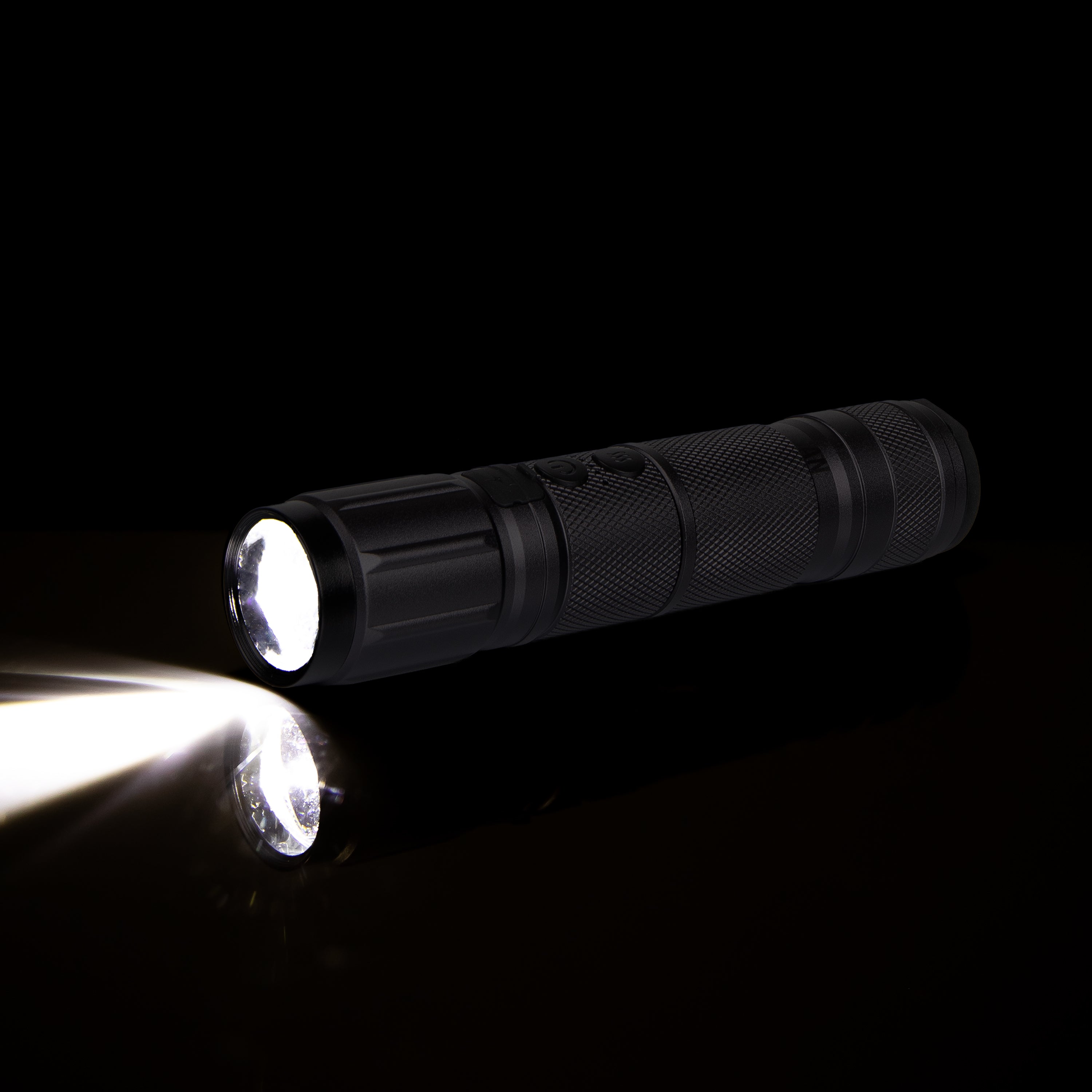 Black LED flashlight shining light on black background, close-up product photo