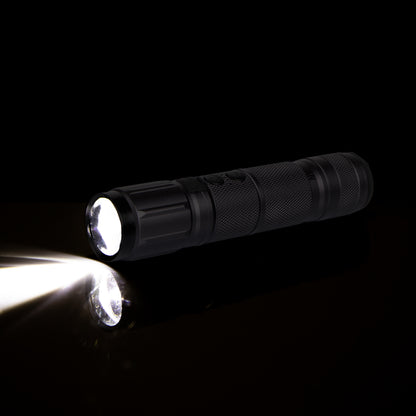 Black LED flashlight shining light on black background, close-up product photo