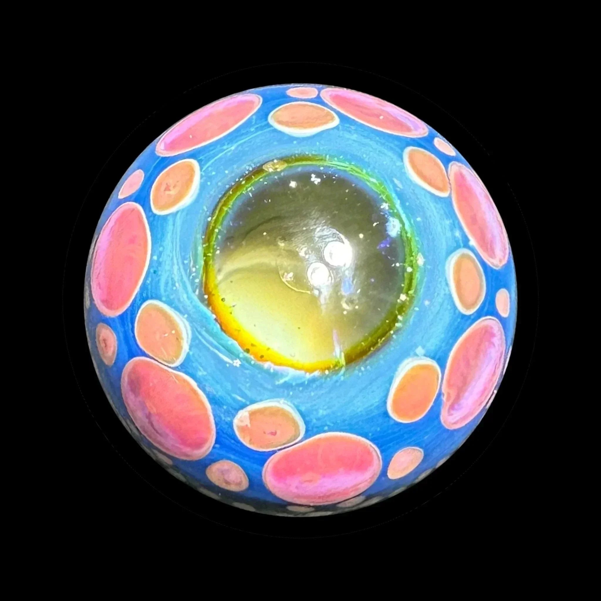 Colorful glass marble with blue, pink, and yellow patterns, viewed on black background