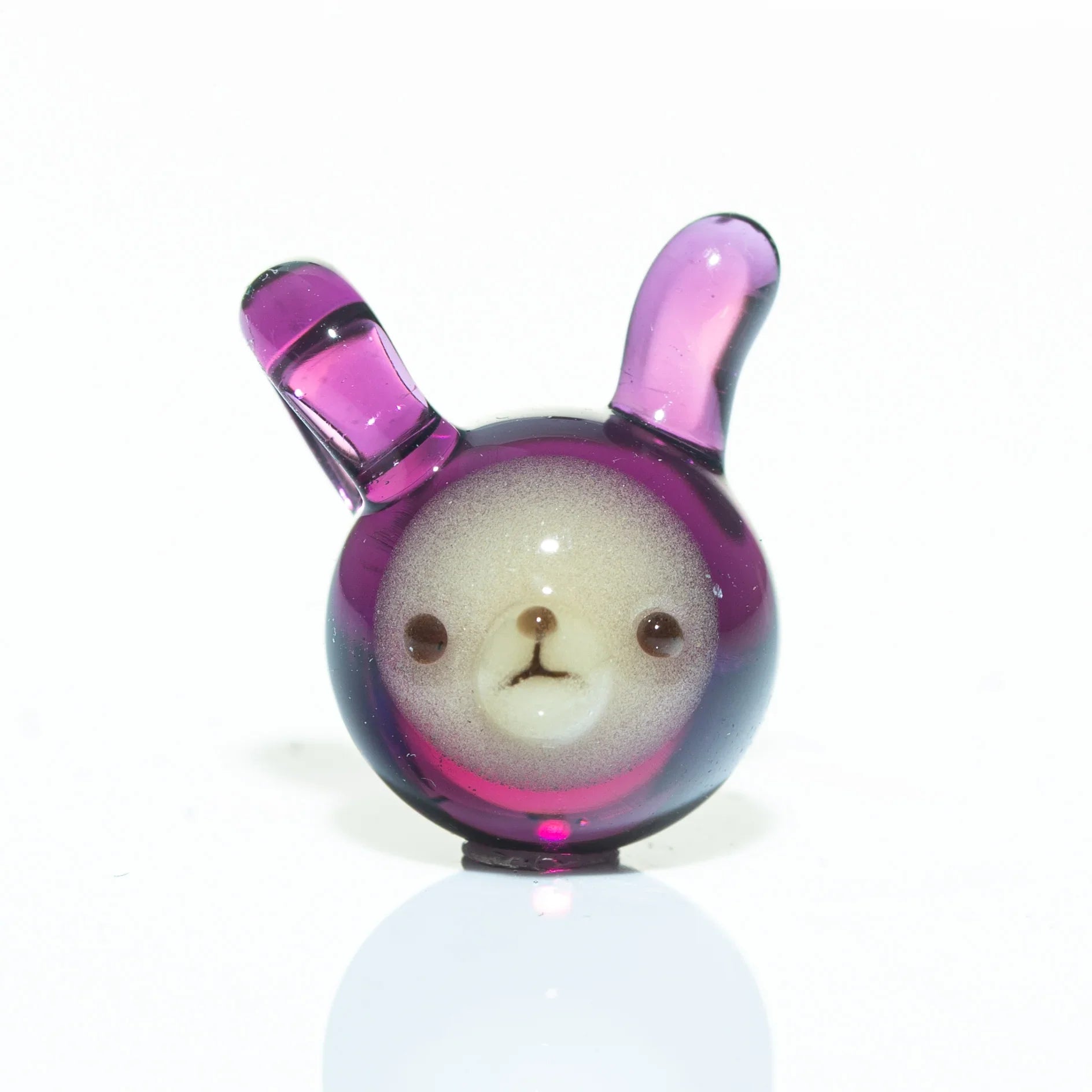 Purple glass pendant shaped like a bear face with upright ears on a white background
