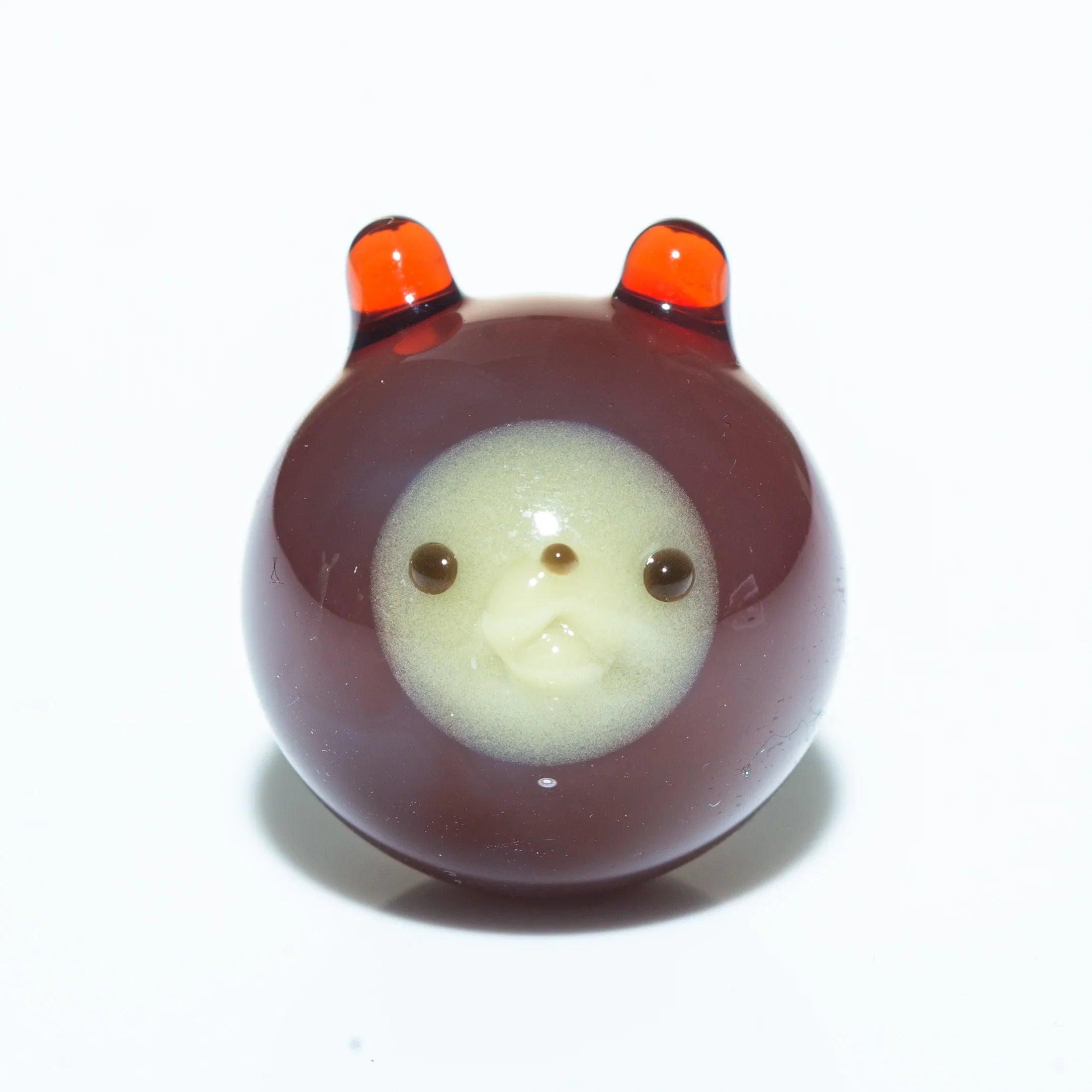 Brown glass animal carb cap with marble design and orange-tipped ears on white background