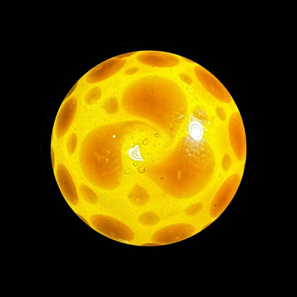 Yellow glass marble with orange bubble patterns on black background