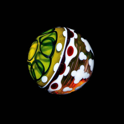 Handcrafted glass marble with green, red, and white patterns on a dark background
