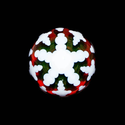 Heady glass marble with white snowflake pattern, red and green accents on black background