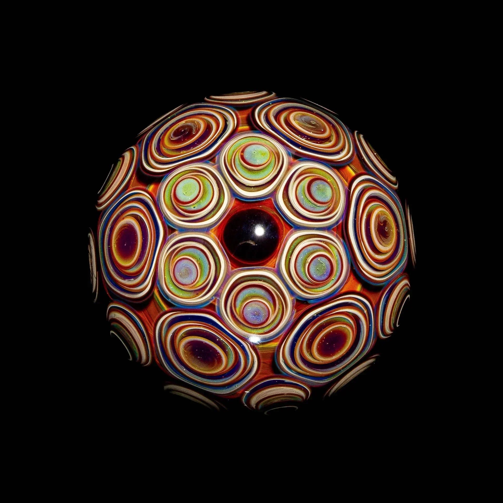 Colorful heady glass marble with intricate layered patterns on a black background