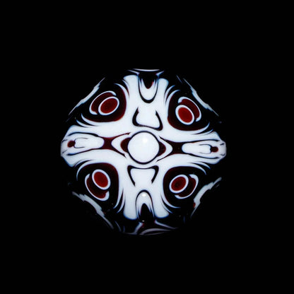 Heady glass marble with intricate black, white, and red abstract patterns on a black background.