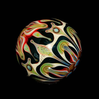Colorful heady glass marble with intricate swirling patterns on a black background