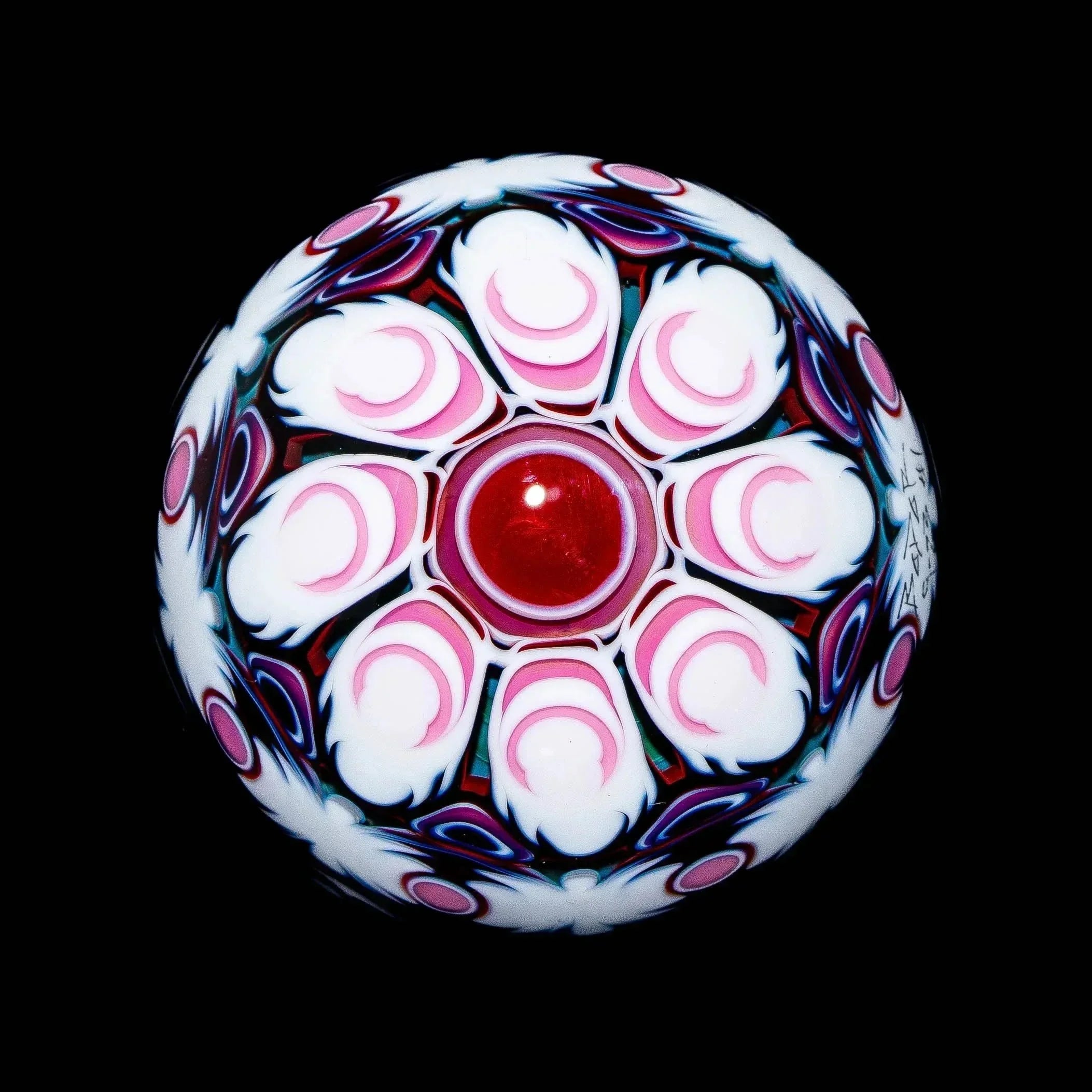 Handcrafted glass marble with red center, intricate pink and white floral pattern